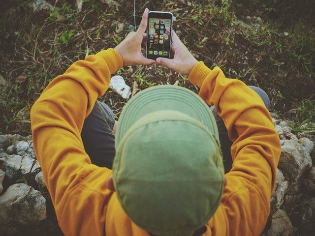 A teen in a hooded sweatshirt looking down at their phone